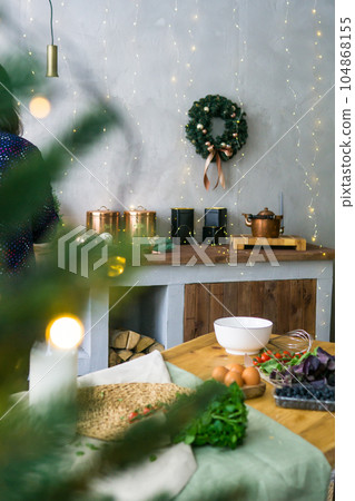 Home New Year's interior. Christmas tree with gifts, decorated with garlands in the kitchen. Cozy atmosphere of a home holiday, loft design of the room, Scandinavian style. Home New Year's interior. Christmas tree with gifts, decorated with garlands in the kitchen. Cozy atmosphere of a home holiday, loft design of the room, Scandinavian style. 104868155
