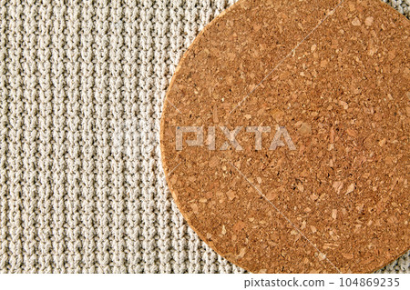 cork stand against a background of rough beige knitted clothes. background for food display 104869235