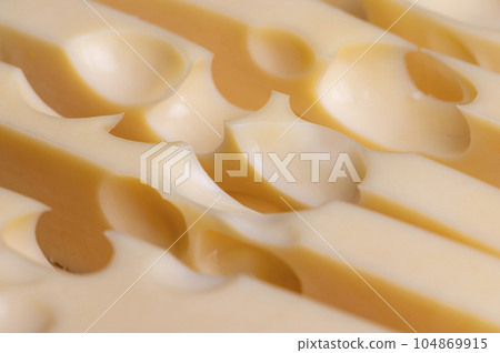 A cut piece of ripe cheese with lots of holes A cut piece of ripe cheese with lots of holes 104869915