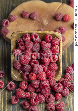 Ripe raspberries on a wooden board Ripe raspberries on a wooden board 104870375
