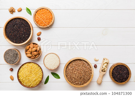 Various superfoods in smal bowl on colored background. Superfood as rice, chia, quinoa, lentils, nuts, sesame seeds, almonds. top view copy space 104871300