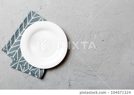 Top view on colored background empty round white plate on tablecloth for food. Empty dish on napkin with space for your design 104871324