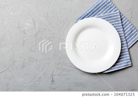 Top view on colored background empty round white plate on tablecloth for food. Empty dish on napkin with space for your design 104871325