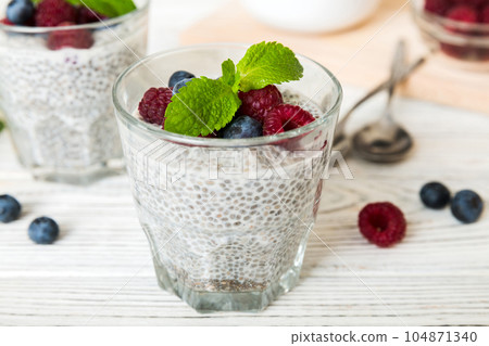 Healthy breakfast or morning with chia seeds vanilla pudding raspberry and blueberry berries on table background, vegetarian food, diet and health concept. Chia pudding with raspberry and blueberry 104871340