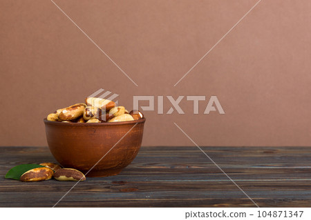 Fresh healthy Brazil nuts in bowl on colored table background. Top view Healthy eating bertholletia concept. Super foods 104871347