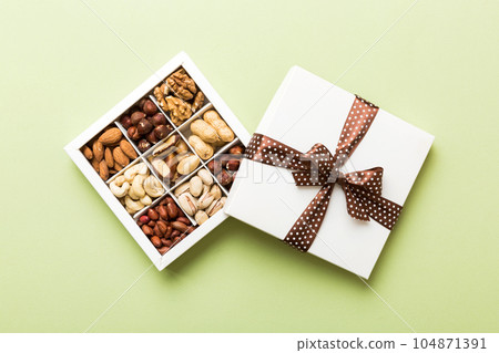 Various varieties of nuts lying in paper box on table background. Top view. Healthy food. Close up, copy space, top view, flat lay. Walnut, pistachios, almonds, hazelnuts and cashews 104871391