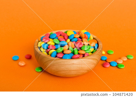 Multicolored candies in a bowl on a colored background. birthday and holiday concept. Top view with copy space 104871420