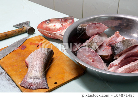 Marinated fish with spices. Before cooking, the hand of the cook smears butter and spices. home cooking concept Marinated fish with spices. Before cooking, the hand of the cook smears butter and spices. home cooking concept 104871485