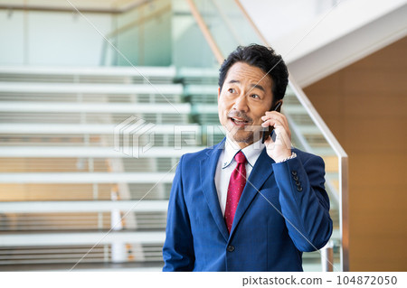 Middle-aged businessman making a phone call in the office Middle-aged businessman making a phone call in the office 104872050