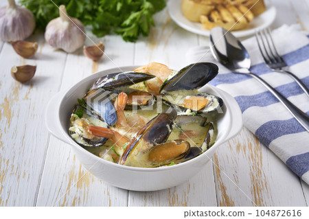 Creamy soup with seafood on a white wooden table. 104872616