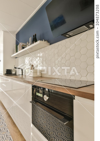 a modern kitchen with hexagon tiles on the backs and wood countertops in white, blue and black 104873208