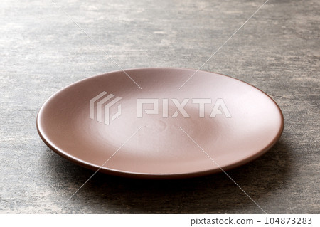 Perspective view of empty plate on cement background. Empty space for your design 104873283