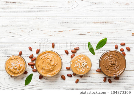 Glass jar with peanut butter on table background, top view space for text and close up Glass jar with peanut butter on table background, top view space for text and close up 104873309