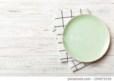 Top view on colored background empty round green plate on tablecloth for food. Empty dish on napkin with space for your design 104873338