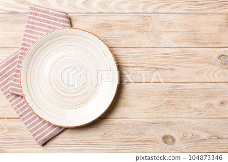 Top view on colored background empty round white plate on tablecloth for food. Empty dish on napkin with space for your design Top view on colored background empty round white plate on tablecloth for food. Empty dish on napkin with space for your design 104873346