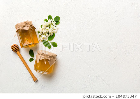 honey jar with acacia flowers and leaves. fresh honey top view flat lay honey jar with acacia flowers and leaves. fresh honey top view flat lay 104873347