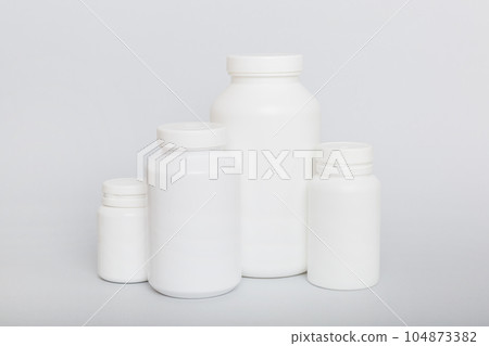 supplement pills with medicine bottle health care and medical top view. Vitamin tablets. Top view mockup bottle for pills and vitamins with green leaves, natural organic bio supplement, copy space 104873382