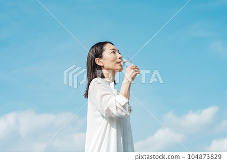 Middle-aged women drinking water from a cup 104873829