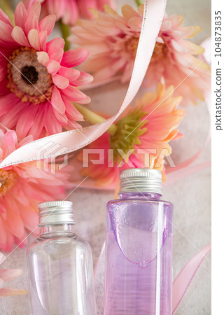 Cosmetic bottle containing cosmetics, flowers and ribbons Cosmetic bottle containing cosmetics, flowers and ribbons 104873835