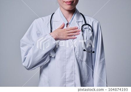 A young female doctor in a white coat who puts her hand on her chest 104874193