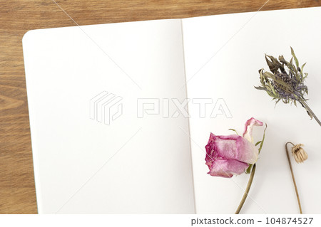 木桌上鋪著白色筆記本上的粉紅玫瑰和刺芹等乾花 104874527