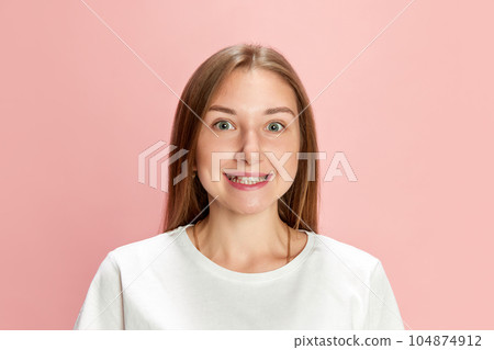 Portrait of young beautiful woman wearing white t-shirt, posing, looking at camera and cheerfully smiling against pink studio background 104874912