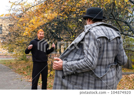 A robber with a knife in a park attacks an exhibitionist A robber with a knife in a park attacks an exhibitionist 104874920