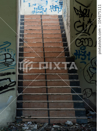 The old cement staircase and the graffiti patterns on cement wall is in the abandoned building and was left to deteriorate over years. The old cement staircase and the graffiti patterns on cement wall is in the abandoned building and was left to deteriorate over years. 104875111