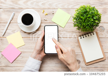 Top view of woman hands holding smart phone with blank copy space screen for your text message or information content. woman hand using phone white screen on top view Top view of woman hands holding smart phone with blank copy space screen for your text message or information content. woman hand using phone white screen on top view 104875203