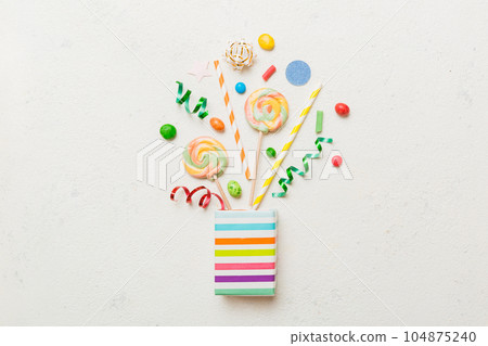 gift box in corner full of assorted traditional candies falling out on colored background with copy space. Happy Holidays sale concept 104875240