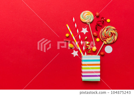 gift box in corner full of assorted traditional candies falling out on colored background with copy space. Happy Holidays sale concept 104875243