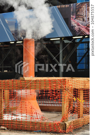 Construction site on a street with a steam spewing pipe 104875557