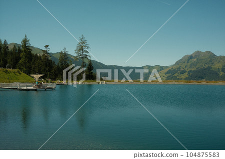 Beautiful view of a calm lake with reflection of trees in the water 104875583