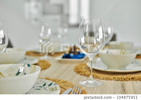 Empty wine glasses and dinnerware served on dining table 104875951