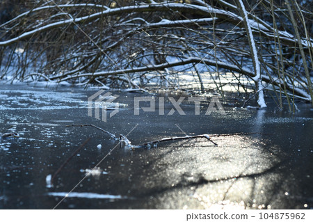 Closeup shot of freezing pond with bright sun reflecting on the surface 104875962