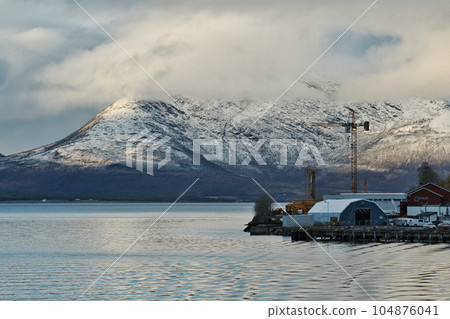 Crane and factory building in the background of snow-covered mountains Crane and factory building in the background of snow-covered mountains 104876041