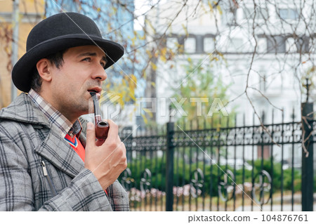 Portrait of a man smoking a pipe on a city street. Portrait of a man smoking a pipe on a city street. 104876761