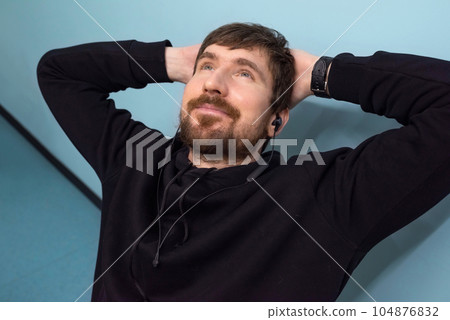 Happy, bearded man relaxing in the office workplace, listening to music on headphones. 104876832