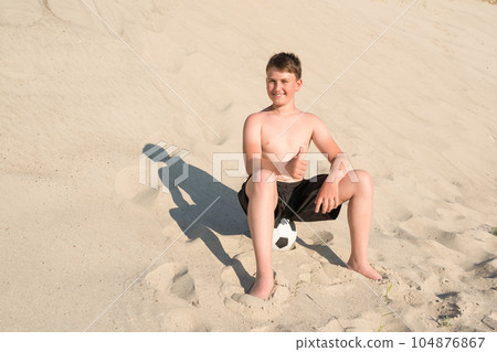 Happy teenager with soccer ball on the beach. Vacation sports games, sports, vacation 104876867