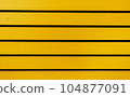 Brightly yellow wooden wall with several horizontal boards. Vivid color, smooth surface with light paint textures. Nice photo for design, wallpaper, background, decorative composition. 104877091