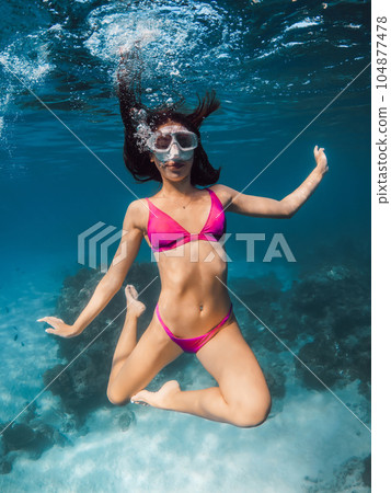 Young woman in bikini fun underwater in transparent ocean. Young woman in bikini fun underwater in transparent ocean. 104877478