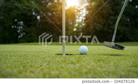 Golf balls that are going to be hole by golfers at the green grass golf course at sunset. Golf balls that are going to be hole by golfers at the green grass golf course at sunset. 104878126