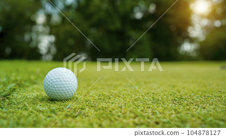 Golf ball on green grass in the evening golf course with sunshine background. Golf ball on green grass in the evening golf course with sunshine background. 104878127