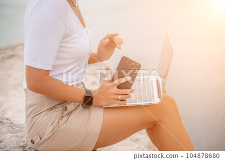 Freelance women sea working on the computer. Good looking middle aged woman typing on a laptop keyboard outdoors with a beautiful sea view. The concept of remote work. Freelance women sea working on the computer. Good looking middle aged woman typing on a laptop keyboard outdoors with a beautiful sea view. The concept of remote work. 104878680