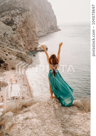 Woman sea green dress. Side view a happy woman with long hair in a long mint dress posing on a beach with calm sea bokeh lights on sunny day. Girl on the nature on blue sky background. Woman sea green dress. Side view a happy woman with long hair in a long mint dress posing on a beach with calm sea bokeh lights on sunny day. Girl on the nature on blue sky background. 104878697