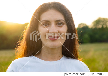 Portrait of a 35-year-old brunette woman looking at the camera smiling in nature. 104879086