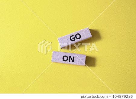 Go on symbol. Wooden blocks with words Go on. Beautiful yellow background. Business and Go on concept. Copy space. Go on symbol. Wooden blocks with words Go on. Beautiful yellow background. Business and Go on concept. Copy space. 104879286