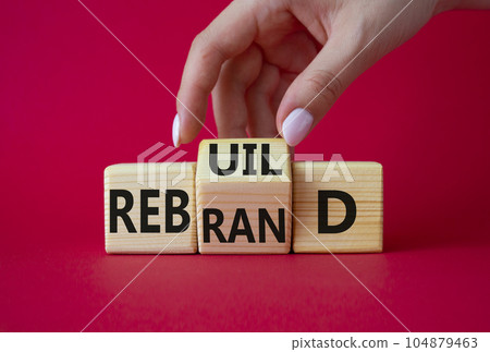 Rebuild and Rebrand symbol. Businessman hand turns wooden cubes and changes the word to Rebrand to Rebuild. Beautiful red background. Rebuild Rebrand and Business concept. Copy space 104879463