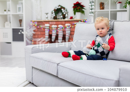 Young child sits on couch in festive clothing 104879910