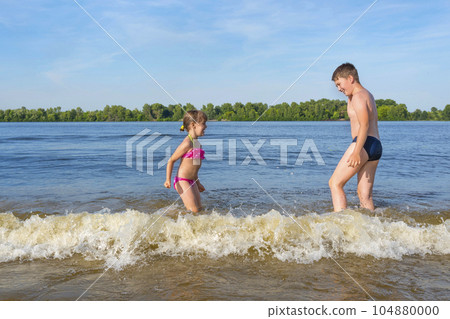 Children play in the water jumping on the waves. Summer holidays 104880000